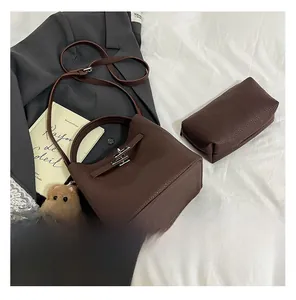 Close-up of dark brown litchi leather bucket bag with silver hardware and bear charm