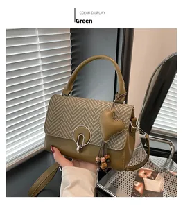 Detail of green houndstooth flap bag with metal ring lock and heart pendant