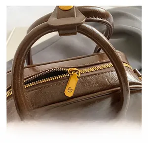 Détail du sac en cuir marron avec garniture dorée et fermeture éclair logotée GM