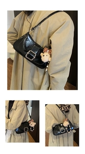 Detail of black glossy patent leather shoulder bag with silver buckle and plush bear charm