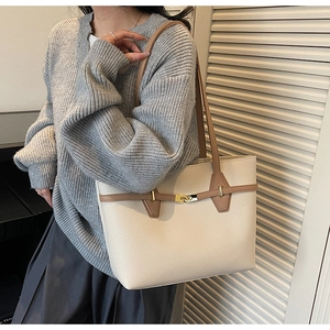 Detail of minimalist cream tote bag featuring lychee grain leather and golden twist lock