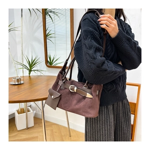 Close-up of brown suede tote bag featuring leather belt strap and mini side pouch accessory