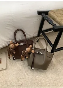 Close-up of leather bucket bags with metal twist locks and plush bear charms