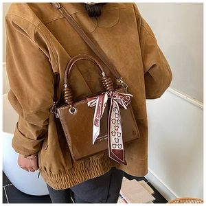 Detail of dark brown leather bucket bag with silk scarf and white letter printing