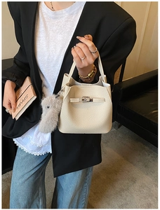 Detail of beige pebbled leather bucket bag with silver turn-lock and plush bunny charm