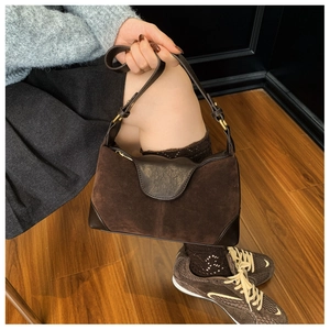 Detail of dark brown suede shoulder bag with leather trim and gold buckle adjustment