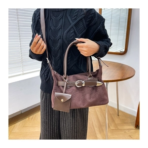 Detail of dark brown suede tote bag with leather strap and decorative silver buckle