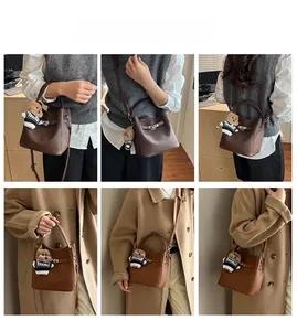 Detail view of brown pebbled leather bucket bag with cute bear charm and lock closure