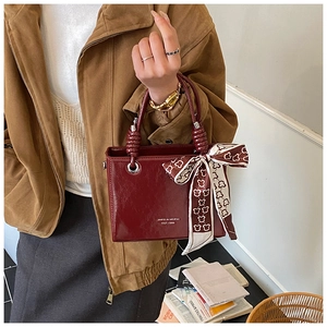 Detail of vintage burgundy leather bucket bag with silk scarf wrapped handle and logo