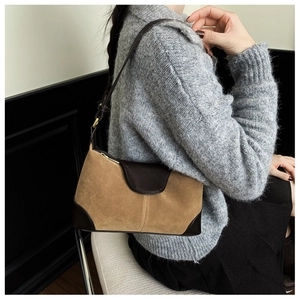 Close-up of a retro brown color-block shoulder bag worn by a model with gold hardware