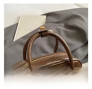 Détail des poignées de sac à main rétro en cuir ciré marron avec rivets dorés