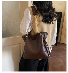 Detail of chocolate brown leather tote featuring geometric stitching and gold chain strap