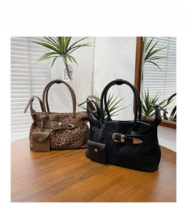 Detail of faux suede tote bags in leopard print and matte black on a wooden table