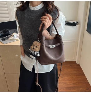 Detail of dark brown lychee leather bucket bag with metal buckle and teddy bear charm