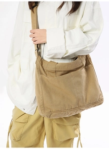 Detailed view of the khaki canvas bag with front pockets and wide adjustable strap