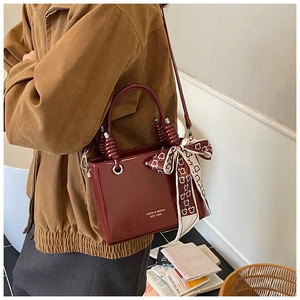 Deep cherry red patent leather crossbody bag with a bear pattern scarf accessory
