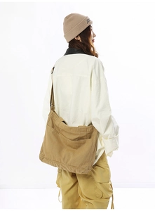 Detail view of khaki canvas crossbody bag showing spacious pockets and wide shoulder strap