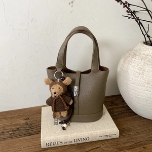 Borsa a secchiello in pelle verde oliva con trama litchi e ciondolo a forma di orso