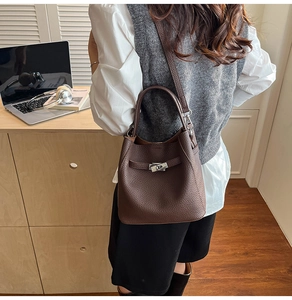Close-up of retro dark brown lychee leather bucket bag with silver metal swivel lock clasp