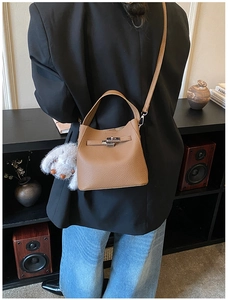 Brown lychee leather bucket bag detail with plush rabbit charm and silver metal buckle