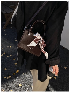 Detail of dark brown vintage faux leather bucket bag with silk scarf on the handle