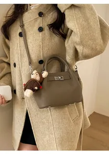 Brown leather bucket bag detail with silver turn-lock and cute teddy bear charm accessory