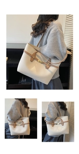 Detail view of large beige tote bag featuring brown leather straps and gold buckle lock