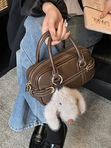 Dark brown leather Boston bag with white stitching and plush rabbit charm detail