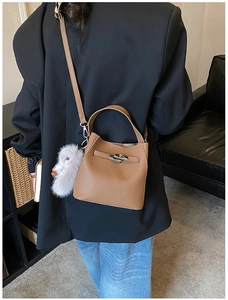 Detailed shot of brown litchi leather bucket bag with silver lock and plush charm