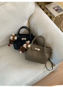Detail of leather bucket bags in black and coffee with metal clasps and bear charms