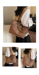 Detail view of large brown pebble leather tote bag with gold twist lock and shoulder strap