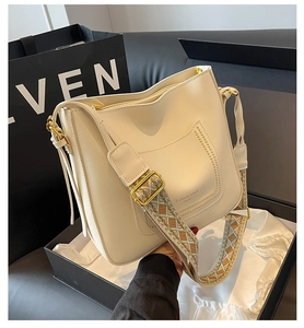 Détail du sac crème avec large bandoulière bohème et finitions métalliques dorées