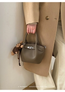 Detail of lychee pattern leather handbag with silver metal buckle and bear charm decoration