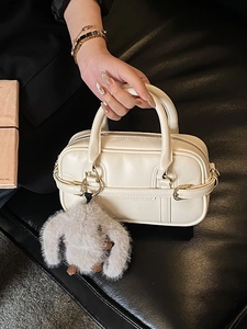 Chic off-white bowling handbag with dual handles and grey rabbit plush pendant