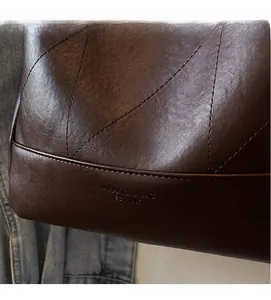 Close-up of vintage brown leather bag featuring large diamond stitching and embossed logo detail