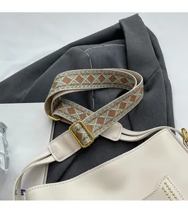 Détail du sac seau blanc avec bandoulière jacquard géométrique et rivets dorés