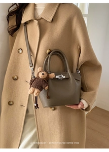 Detail of lychee pattern leather bucket bag with silver lock and plush bear charm