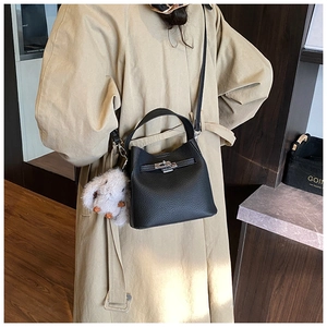 Detail of black lychee leather bucket bag with silver clasp and plush rabbit charm decor