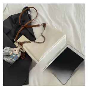 Détail du sac demi-lune en cuir blanc cassé avec chaîne et accessoire pendentif ours