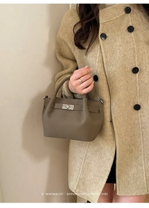 Detail shot of a minimalist khaki leather bucket bag with metallic twist lock closure