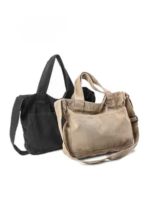Front pocket details of washed canvas tote bags in black and khaki with long straps