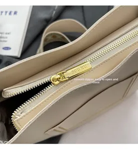 Gros plan sur la fermeture éclair dorée d'un sac cabas beige avec détails gravés