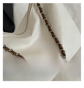 Détail d'un sac cabas en PU blanc avec chaîne en métal et bandoulière tressée
