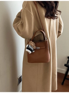 Retro brown bucket bag with teddy bear charm worn with a stylish wool coat