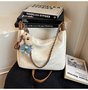 Détail du sac demi-lune blanc avec garniture en cuir marron et breloque ours mignon