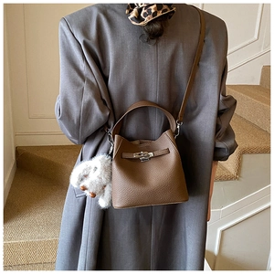 Brown lychee leather bucket bag with silver lock and plush bunny charm on a model