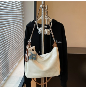 Détail d'un sac hobo en cuir blanc avec chaîne argentée et charmant pendentif ours