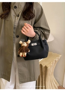 Detail of black pebbled leather bucket bag with silver twist lock and bear charm