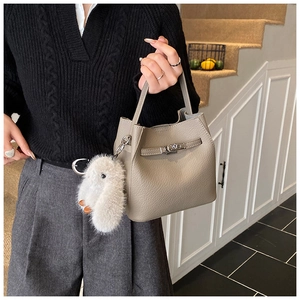 Detail of beige bucket bag with silver twist lock and plush bunny charm on a model