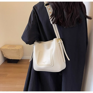 Détail du sac seau blanc cassé avec bandoulière tissée et poignée en cuir réglable
